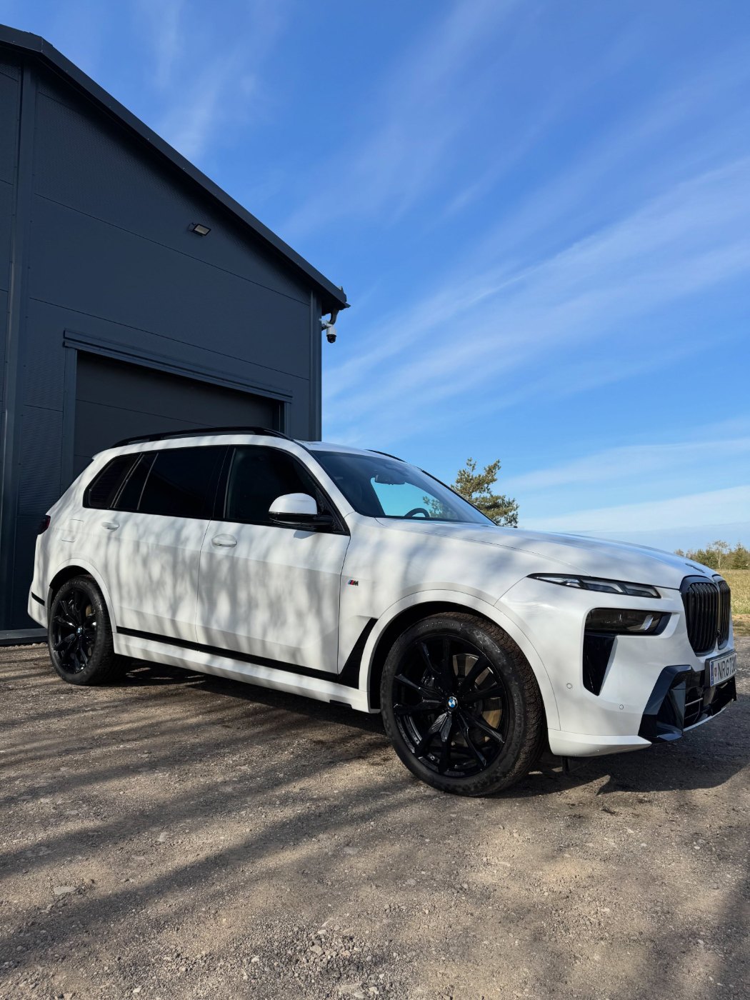 Baltas BMW X7 prie Auto Korekcija studijos pastato